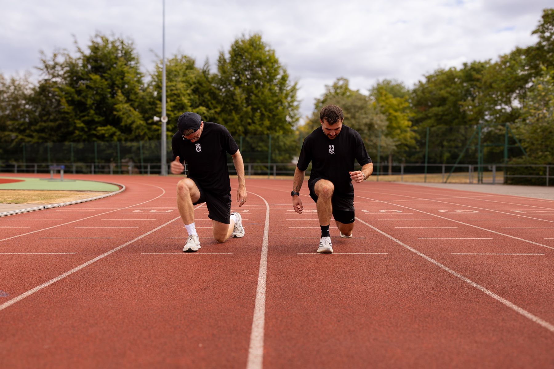 Two members kneeling at the start of a running track, about to set off